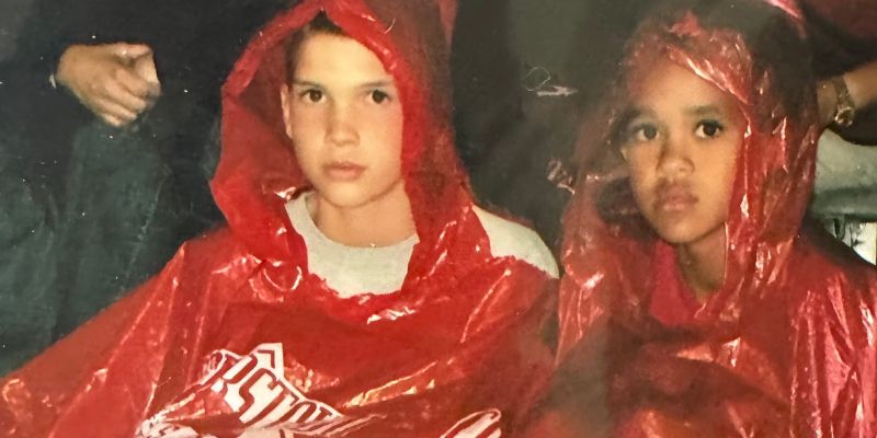 Left to right: Reece Elliot and Derrick White as kids. Both are wearing read rain ponchos.